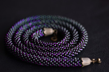 Fototapeta premium Close-up of a long violet bead necklace on a dark background