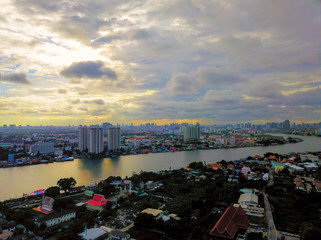 Fototapeta na wymiar Beautiful sunset sky above the city and river with sky blue and orange light of the sun through the clouds in the sky, Orange and red dramatic colors, Warm color - Image