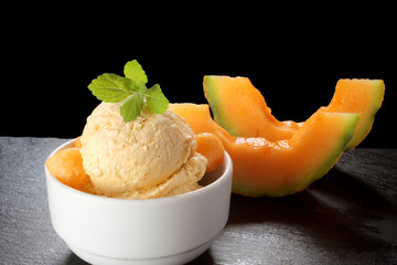 Fresh melon ice cream with melon and melissa on black background