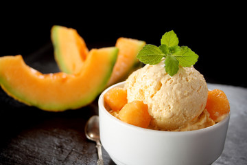 Fresh melon ice cream with melon and melissa on black background
