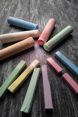 Colored chalk for drawing laid out on a black chalkboard .