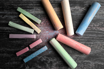 Colored chalk for drawing laid out on a black chalkboard .