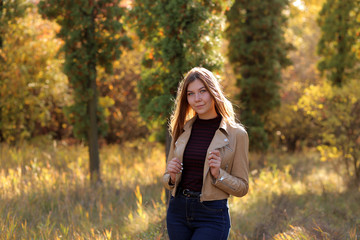 Sweet young sensual sexy woman walking in autumn park. Girl adorable blonde posing in warm and cozy outfit autumn nature background. Autumn woman having fun at the park and smiling.
