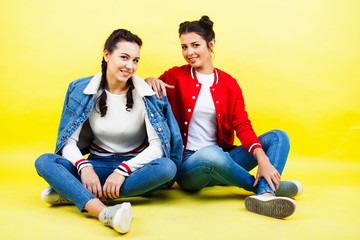 lifestyle people concept: two pretty young school teenage girls having fun happy smiling on yellow background