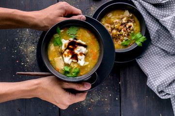 Male hands hold a plate of homemade pea soup with chicken meat, vegetables and parsley. Homemade Food Concept. Top view