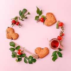 Ingredinets for winter fall autumn seasonal beverage tea party - fresh rose hip berries, honey, apple and heart-shaped biscuits. Concept of cozy teaparty witn immunity drink