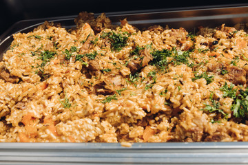 Extreme close-up fresh appetizing pilaf with meat and greenery decorating serving on plate top view. Juicy fragrance hot traditional Uzbek dish ready for eating