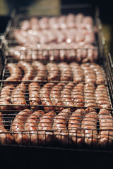Close-up of delicious chicken or pork sausages on BBQ. Unrecognizable cook preparing tasty sausages on grill.