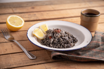 Plate of black rice with squid and prawns or Valencian black paella