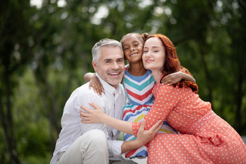 Grey-haired smiling man standing near wife and daughter