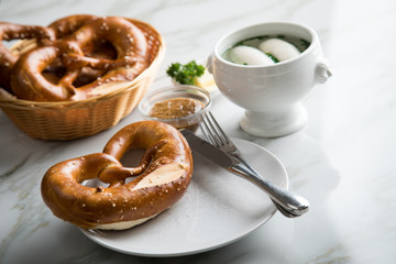 Münchener Weißwurst in Terrine mit bayrischer süßen Senf, Brezel und Butter auf Marmor Tisch