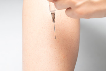 An extreme closeup view on the pointed and sharp end of a hypodermic needle, as a diabetes sufferer injects insulin to stabilize blood sugar levels.