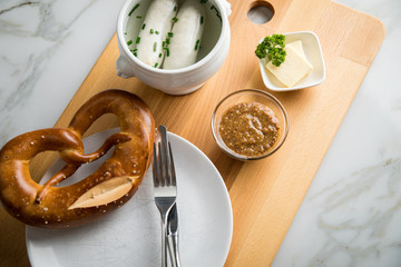 Münchener Weißwurst in Terrine mit bayrischer süßen Senf, Brezel und Butter auf Holz Brett