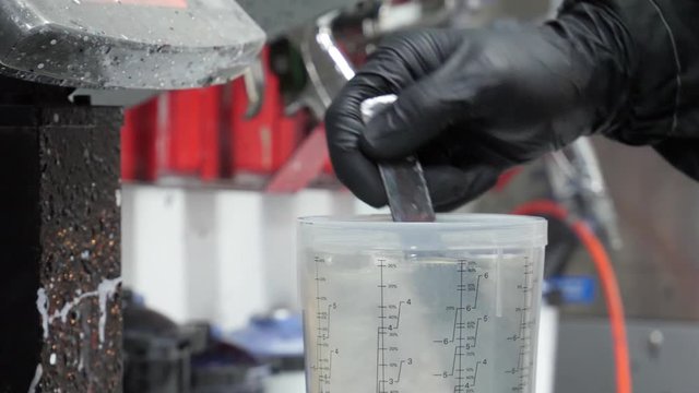 Autobody technician mixes clear coat to use in a spray gun