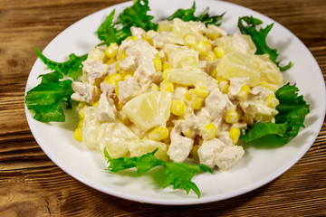 Festive salad with chicken breast, sweet corn, canned pineapple and mayonnaise on wooden table