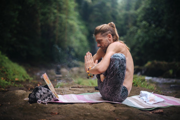 Yoga practice and meditation in nature. Man practicing near river
