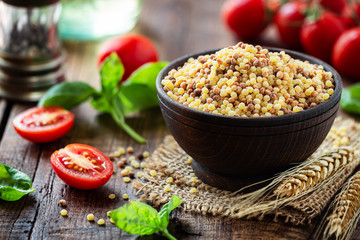 Fregola sarda with red ripe tomatoes and fresh basil - traditional durum wheat ball shaped toasted...