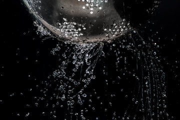 Obraz na płótnie Canvas Flow and drops of water through holes in a colander on a dark background
