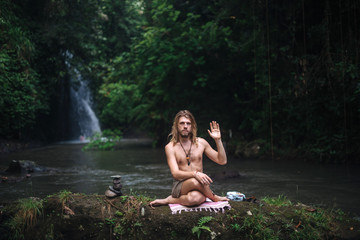 Fototapeta premium Yoga practice and meditation in nature. Man practicing near river