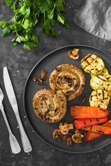 Grilled sausages on a black plate on a dark background
