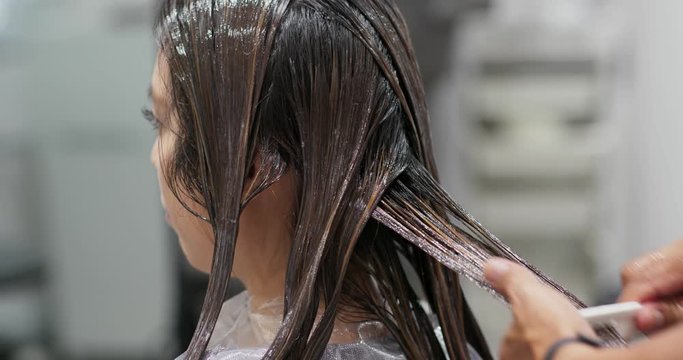 Woman having hair straightening treatment in hair salon