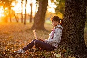 Woman working on laptop under the tree in park