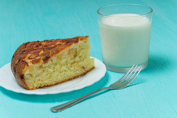 Apple pie, fork, glass of milk on blue wooden background