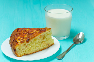 Apple pie and spoon and glass of milk on blue