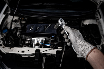 Engine check concept. Close up hand doing car service. Tight nut by socket block.
