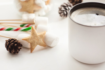 Obraz na płótnie Canvas Cup of hot Chocolate drink with marshmallows, cinnamon sticks, anise star, gift and cones on white background. Winter christmas holiday background.