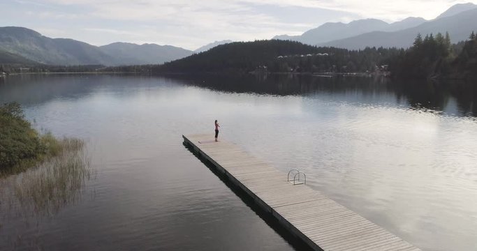 Woman Meditating On A Pier At The Lake