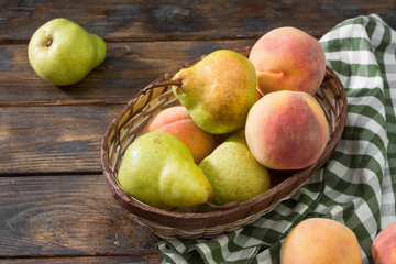 Pears and peaches in a basket on a wooden table. Rustic style