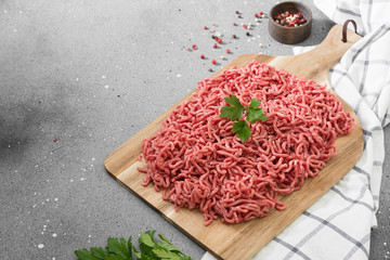 Ground beef on a wooden Board on a grey table