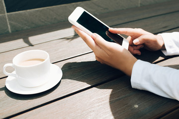 Woman hand texting for someone with black screen at coffee shop
