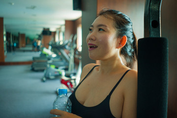 young happy and attractive Asian Korean woman drinking water during fitness center workout smiling cheerful training at hotel gym in body care and healthy lifestyle concept