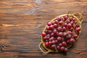 Tray with ripe sweet grapes on wooden background