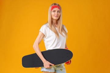 Beautiful and fashion teenager posing with a skateboard in studio