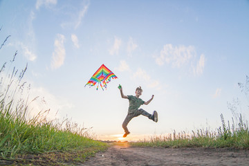 A child plays with a kite at sunset in the field.