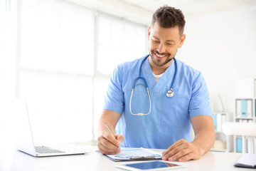 Fototapeta premium Male nurse working at table in clinic