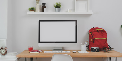 Modern workplace with desktop computer and office supplies with red backpack