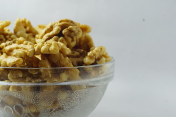 side view of fresh raw walnut in a bowl with white background