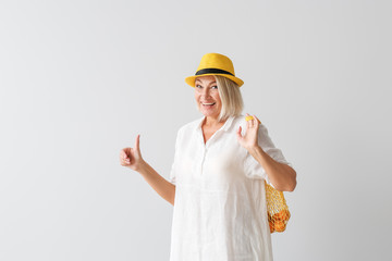 Mature woman with eco bag showing thumb-up on light background
