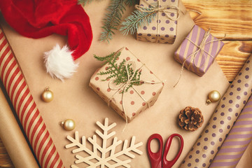 Fototapeta na wymiar Christmas festive mood. Flat-lay of decorations, ribbons, gift paper, wrapped gift on wooden background