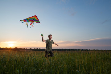 A child plays with a kite at sunset in the field.