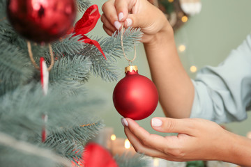 Woman decorating beautiful Christmas tree at home, closeup