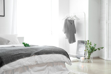 Stylish interior of bedroom with clothes hanger and eucalyptus branches