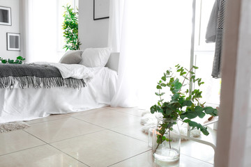 Green eucalyptus branches in jar on floor in bedroom © Pixel-Shot