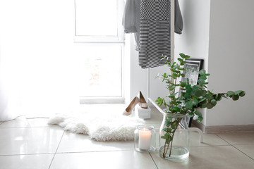 Green eucalyptus branches in jar with candle on floor in room © Pixel-Shot