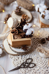 Family time to wrap christmas presents! Ideas for hand made gifts decor in rustic style, natural ingredients, cozy mood. Wooden background, scissors, lace, cones, cinnamon and cotton. Zero waste 