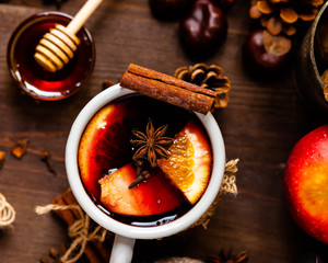 Cozy time at home with a metal mug of hot mulled wine. Autumn, warm clothes, natural ingredients, spice, fruit and honey. Corkscrew to open wine. Rustic decor, festive mood. Flat lay top view